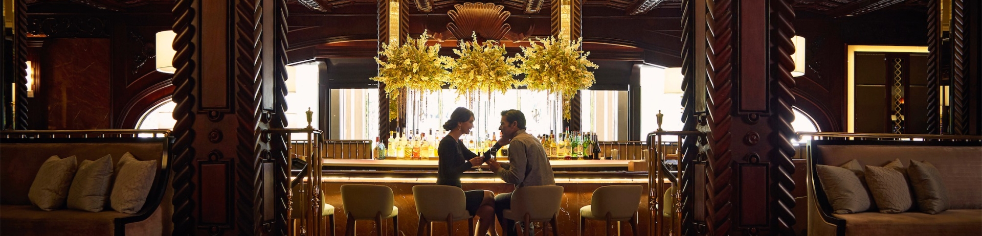 a couple sitting at the chandelier bar