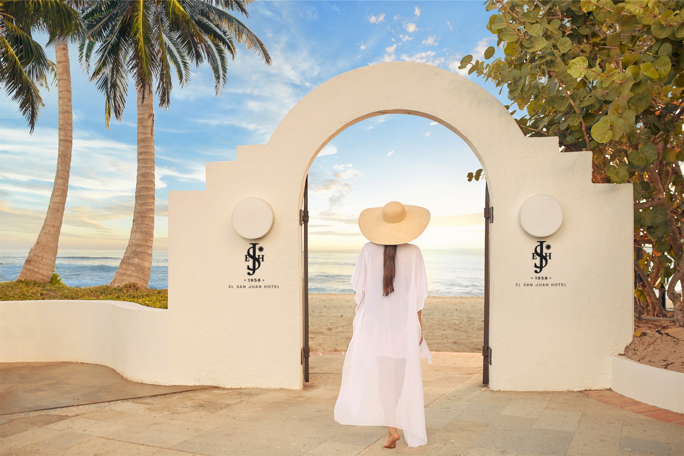 woman walking through an archway to the beach