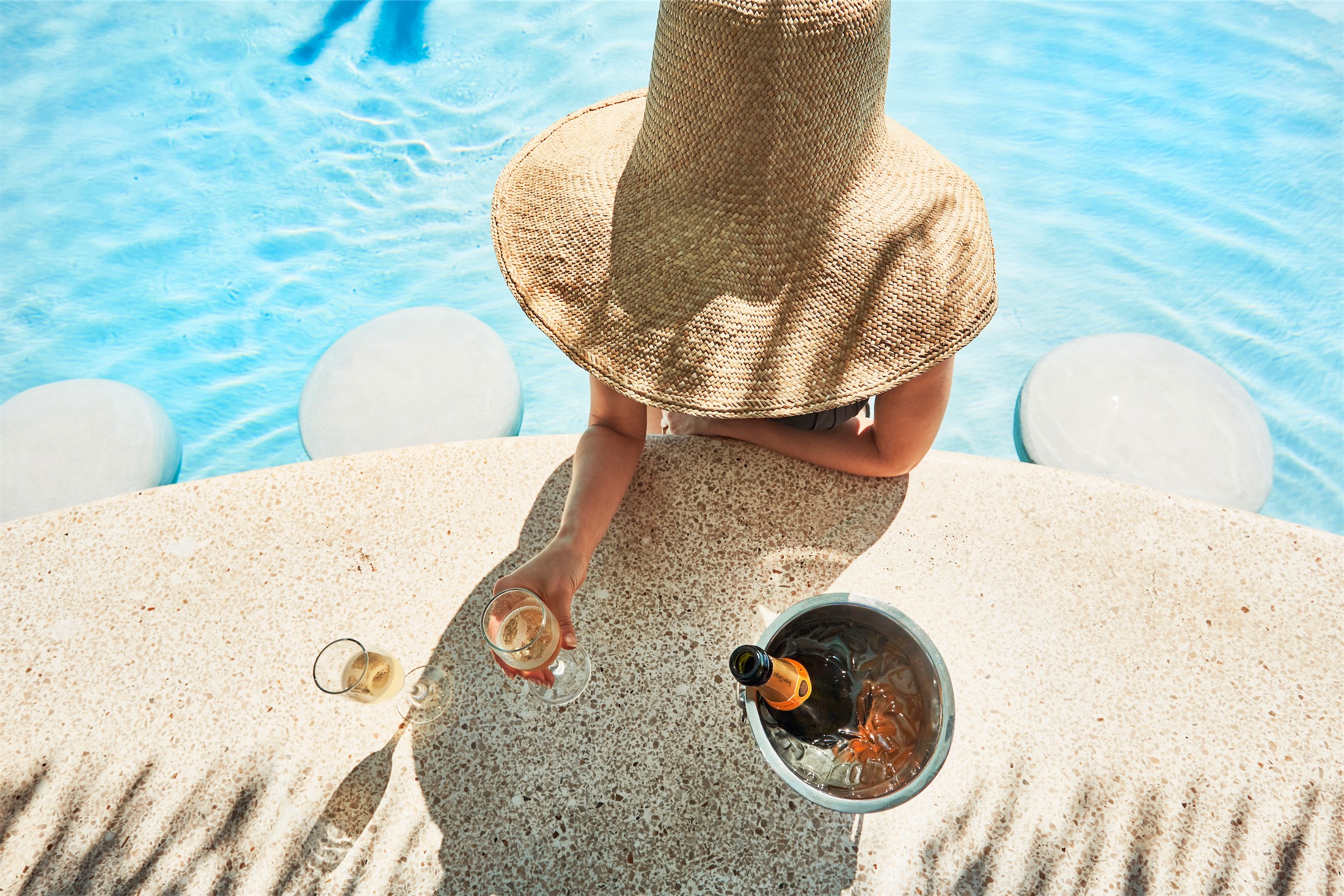 woman in a large hat sitting and eating in the pool