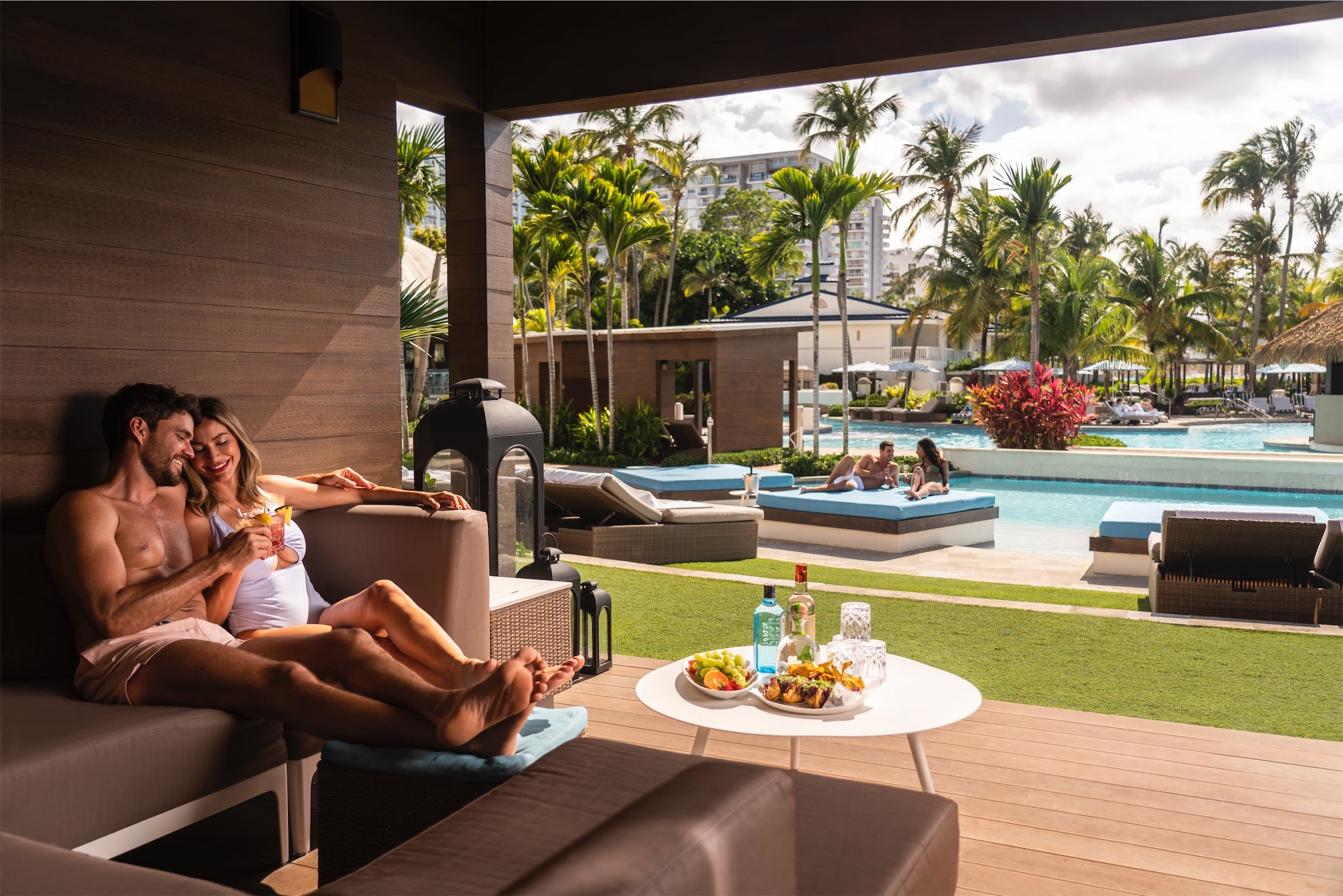 couple lounging with food and drinks by the pool