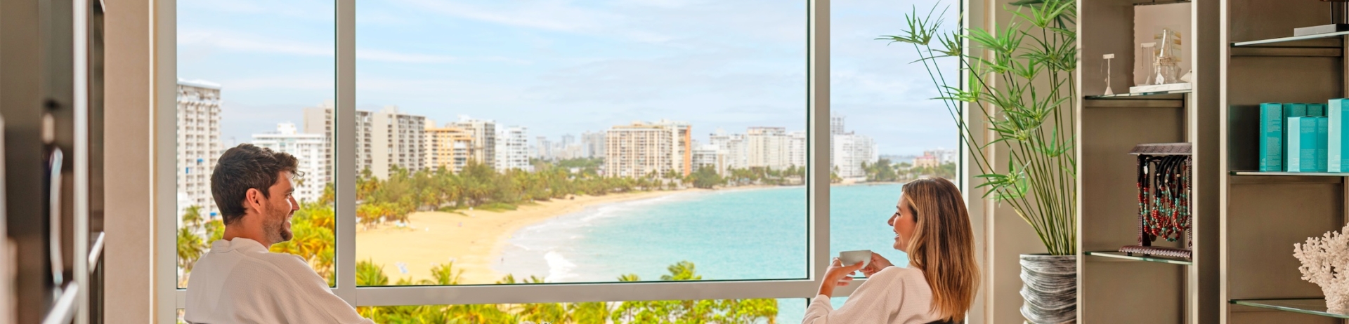 pareja sentada junto a una ventana con vistas al océano