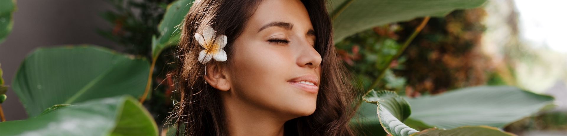 woman standing next to large plant leaves