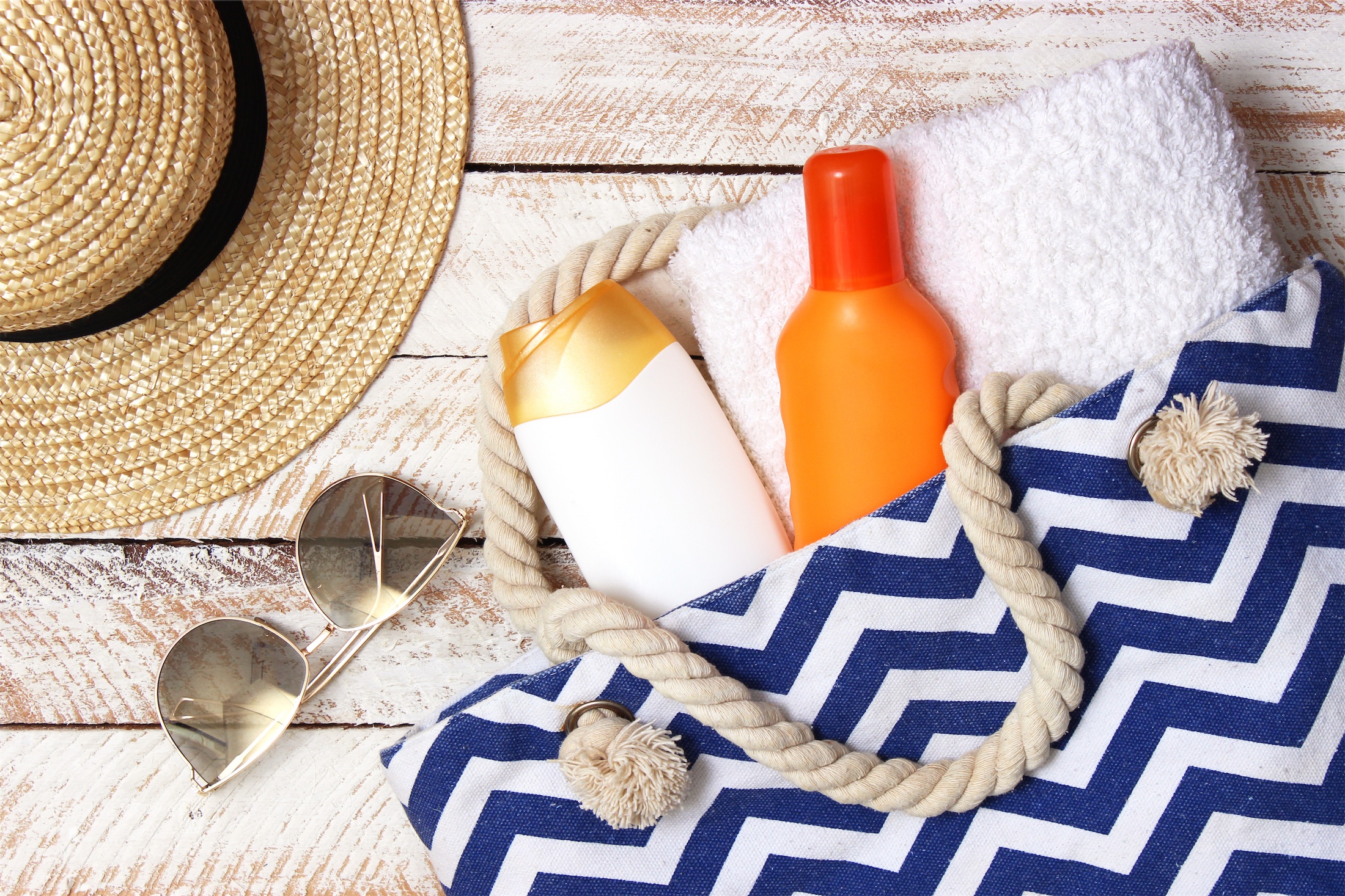 bottles of sunscreen in a bag next to sunglasses