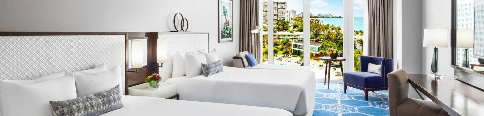 two queen sized beds in a room overlooking a pool