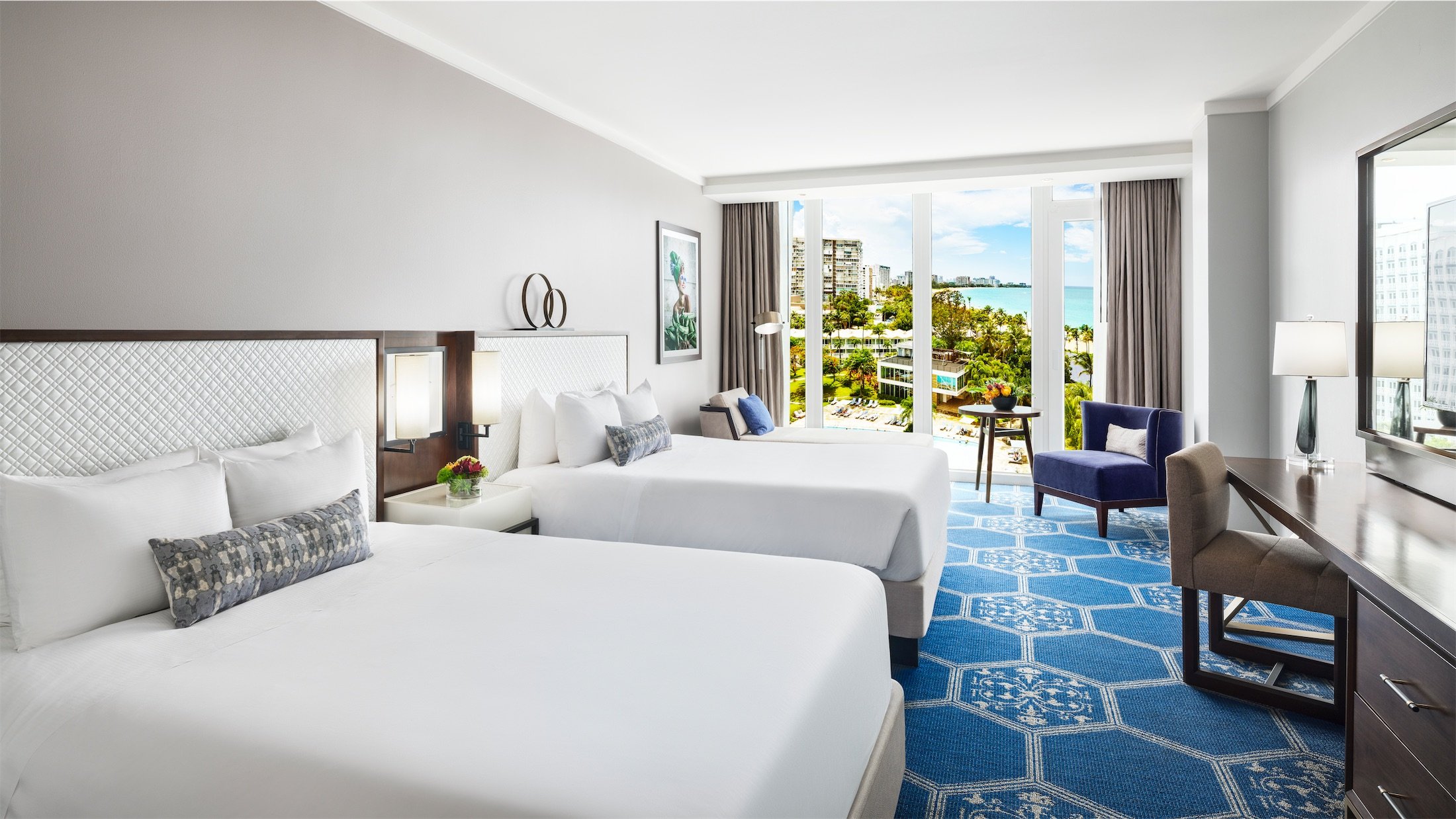 two queen sized beds in a room overlooking a pool