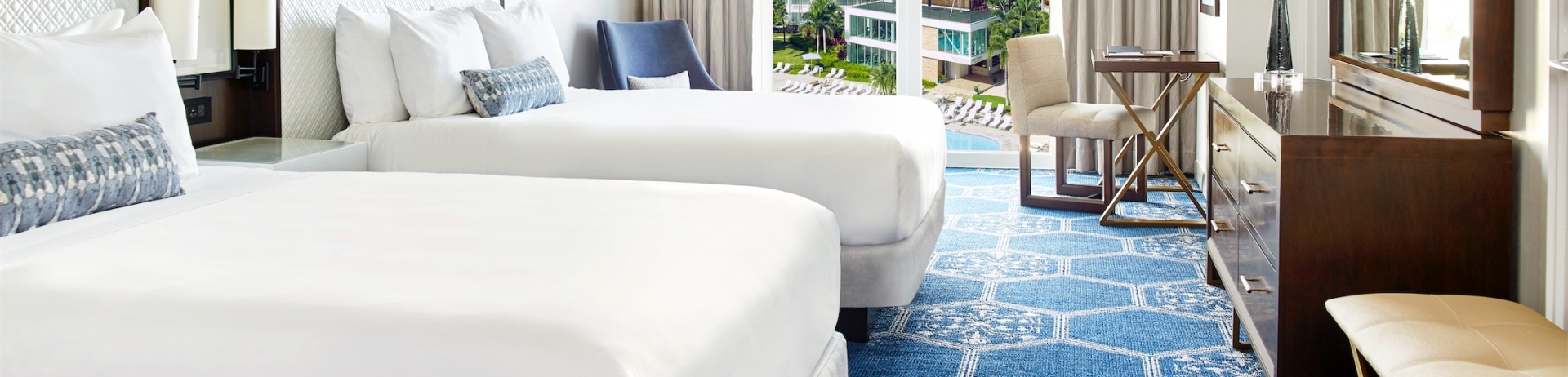 two queen sized beds in a room overlooking a pool area