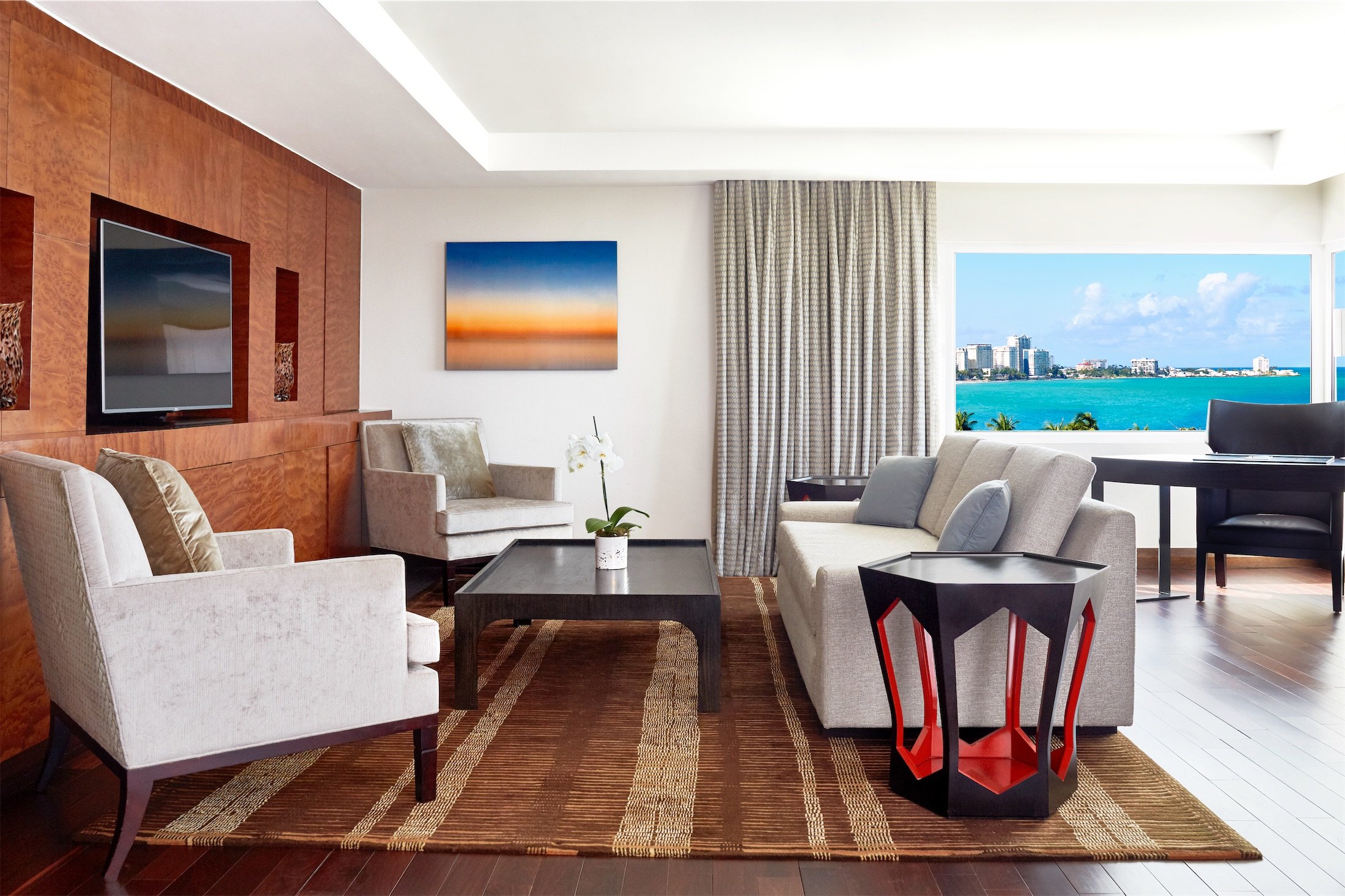 living room area with large rug and red and black side table