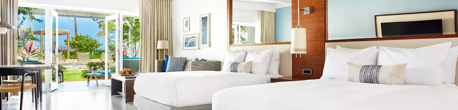 two queen sized beds in a room leading to an outdoor area