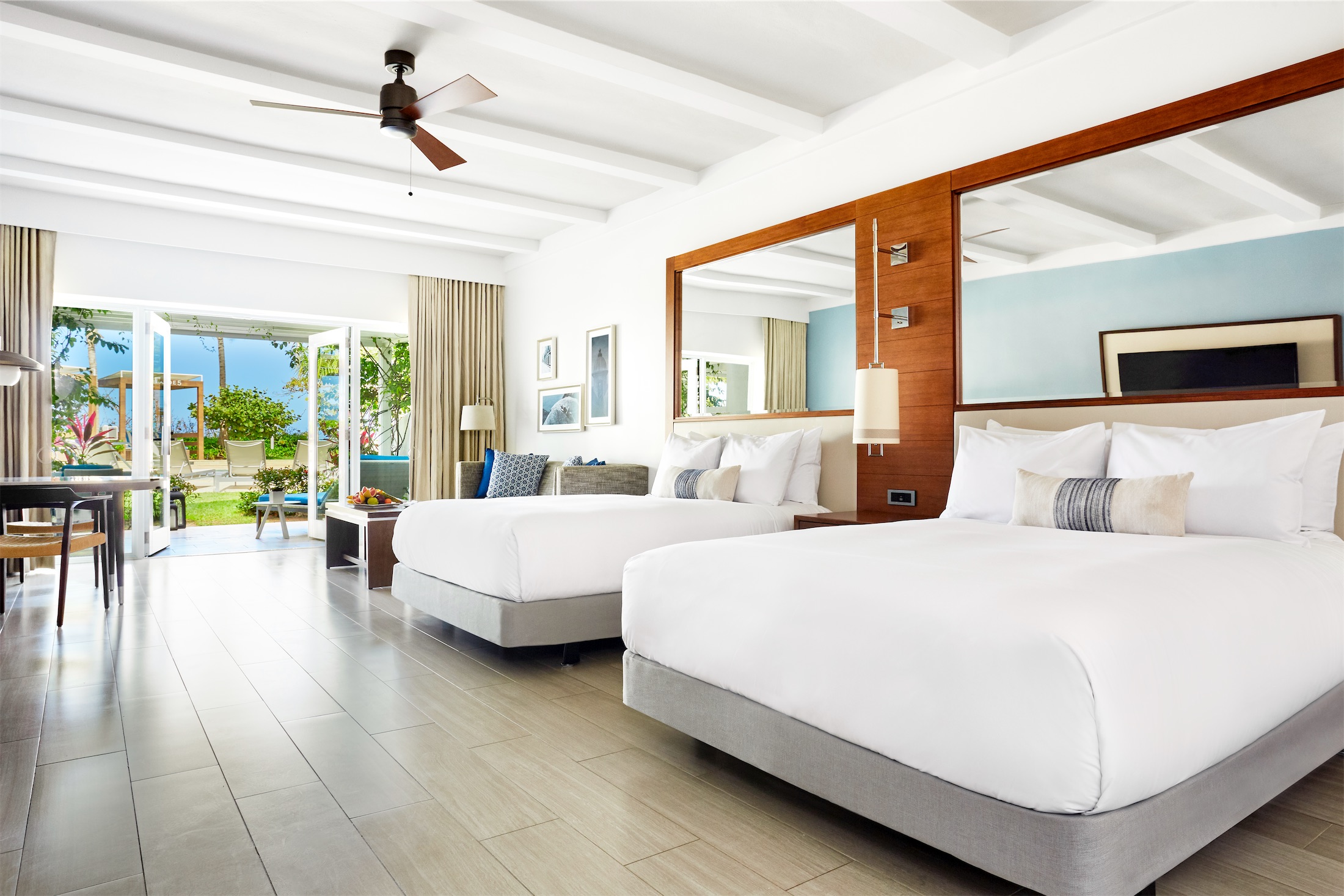 two queen sized beds in a room leading to an outdoor area