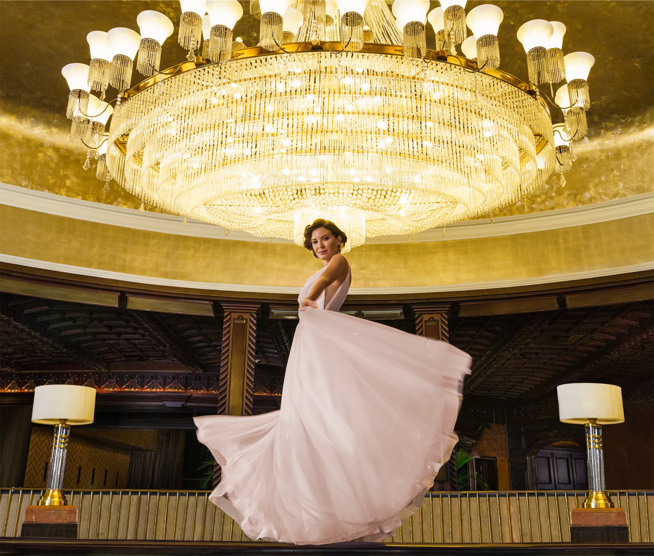 woman in a dress under a large chandelier