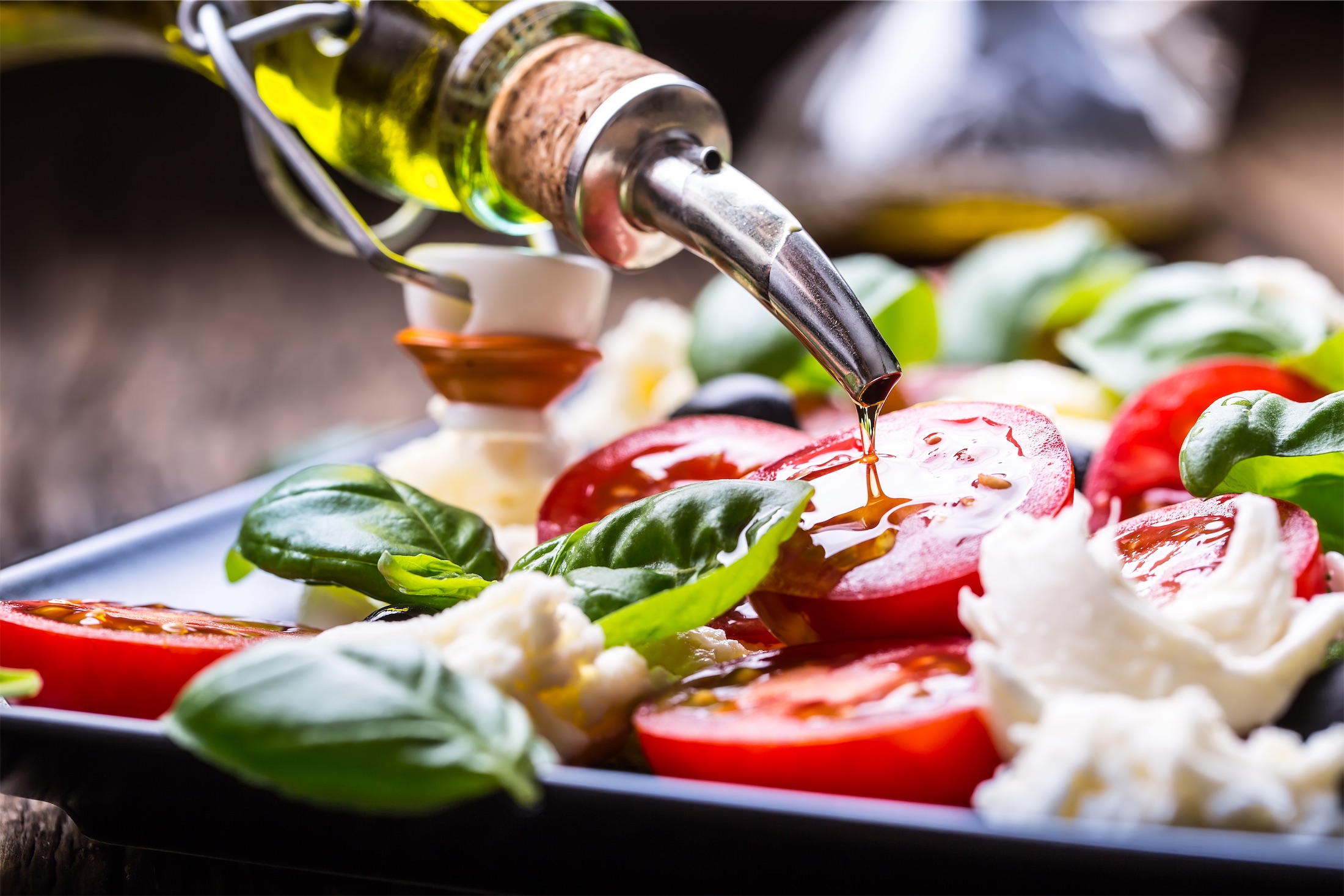 close up of olive oil being poured on a salad