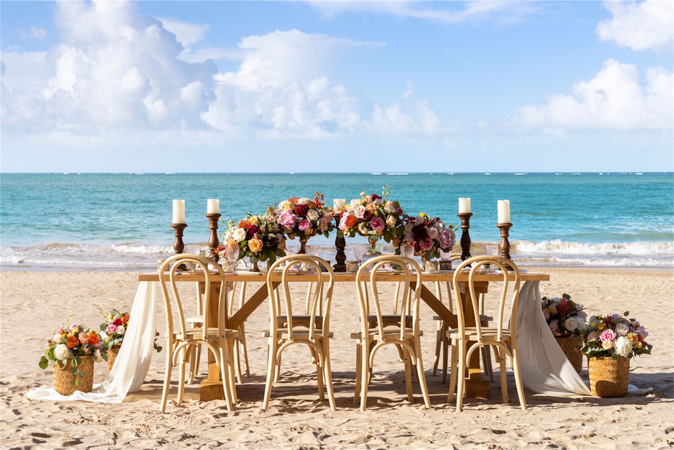table with four chairs set up for a wedding on a beach