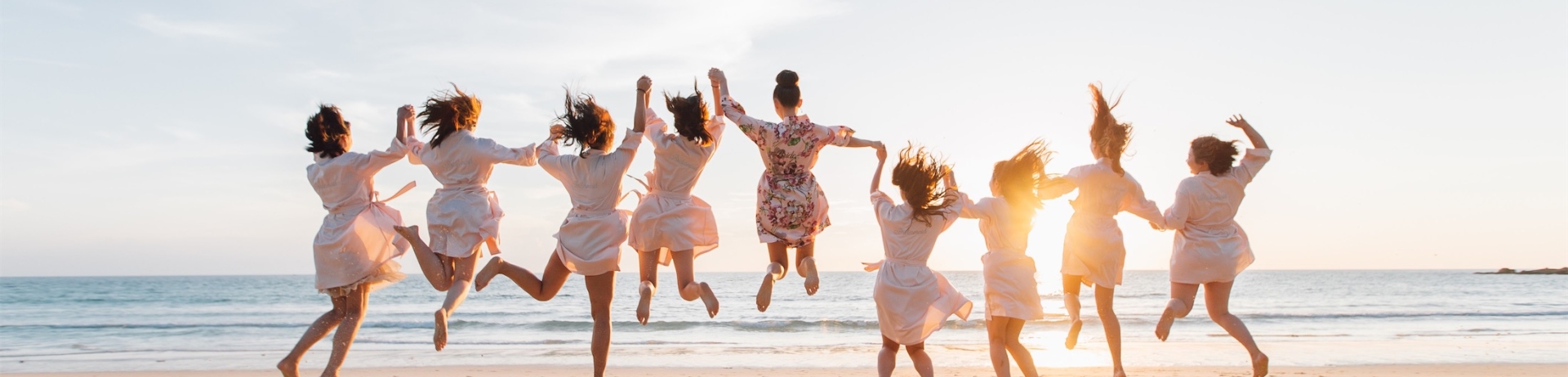 group of friends holding hands and jumping on the beach