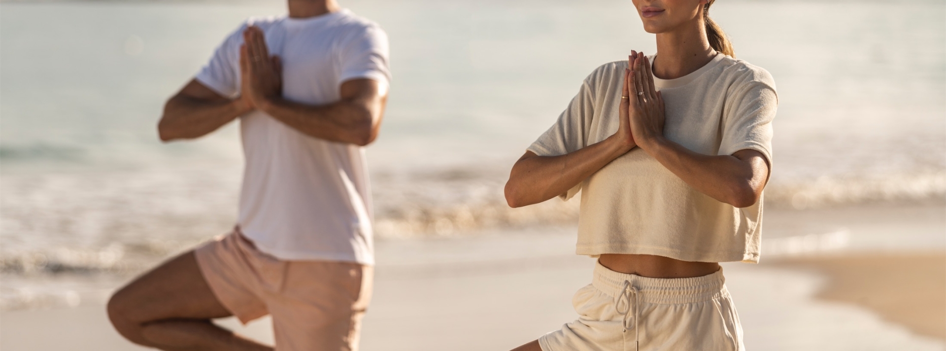 dos personas haciendo yoga en la playa