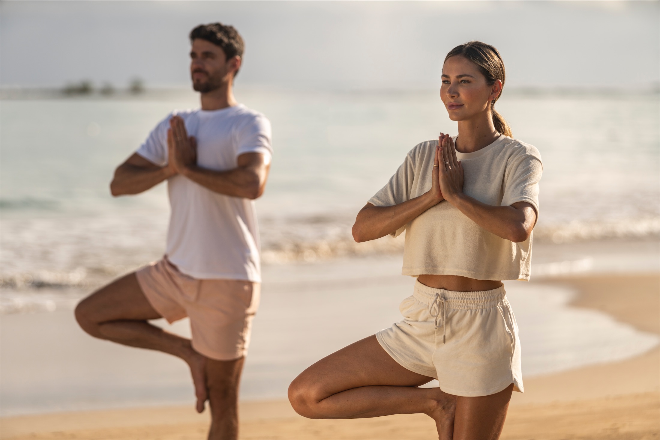 couple doing yoga on the beach