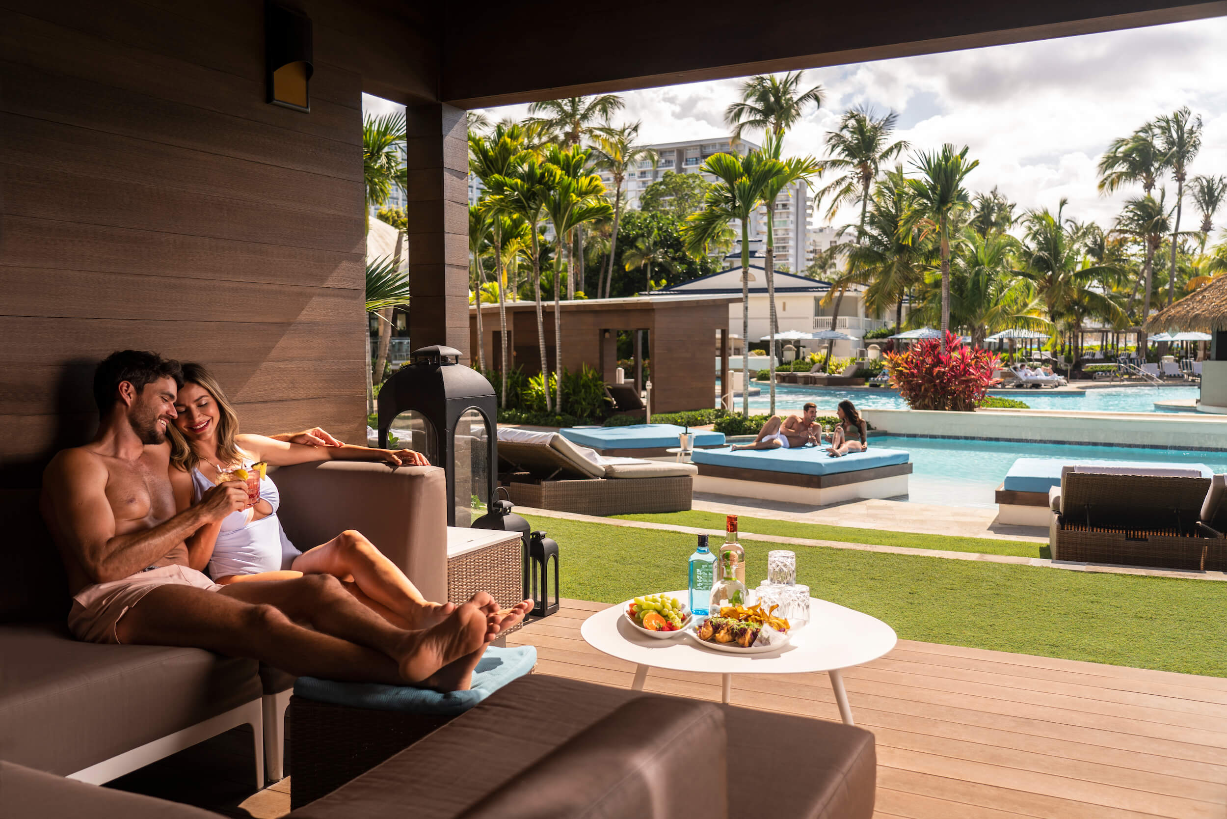 pareja compartiendo comida y bebida junto a una piscina