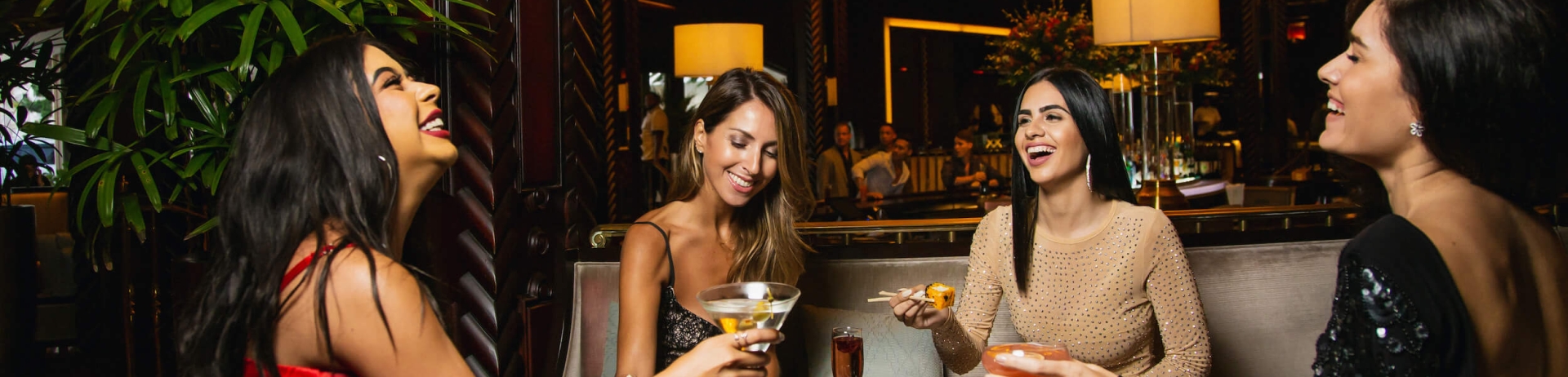 4 friends sitting around a table with food and drinks